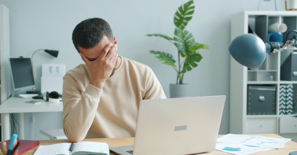 パソコンの前で難解なニュース画面を見て少し困った表情を浮かべる、50代の落ち着いたビジネスパーソン。