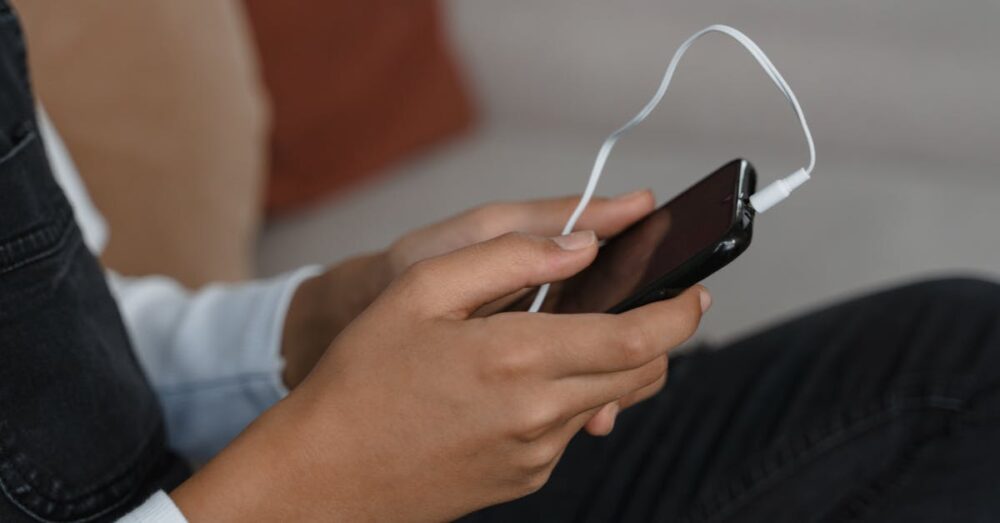 電車内でワイヤレスイヤホンを装着し、スマートフォンの画面を見ている人物の様子。NotebookLMの音声解説機能を使って、移動中に効率よく学習しているシーンを表現している。