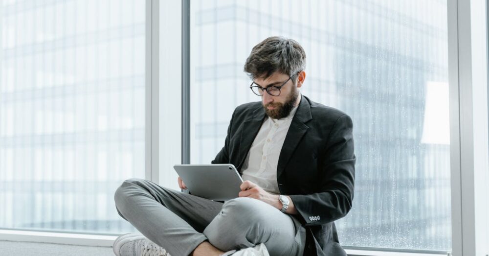 パソコンの前で難解なニュース画面を見て少し困った表情を浮かべる、50代の落ち着いたビジネスパーソン。