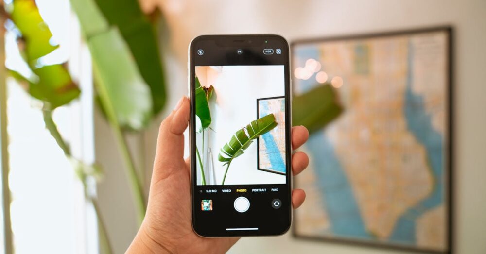 家電量販店の店頭で、スマートフォンを使って洗濯機のスペック表やPOPを撮影している様子。買い物中の情報収集シーンを表現している。