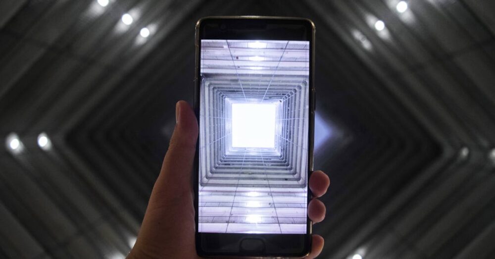 スマートフォンの画面越しに広がる、明るく開けた未来の都市の風景。AI技術が人々の生活をより豊かで知的なものへと導くイメージを象徴している。